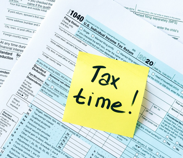 A 1040 federal income tax form with a yellow note on top that reads "Tax time!"